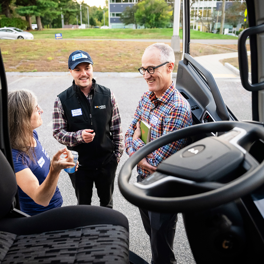 Three people conversing just outside an electric truck