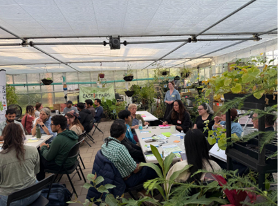 People sitting at tables in a greenhouse.