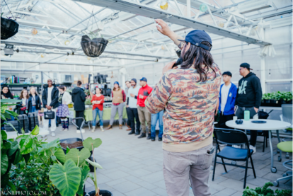 Man speaking to group in a greenhouse.