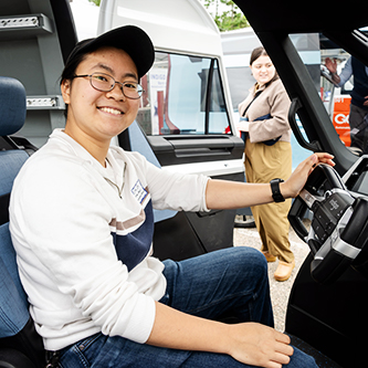 A person trying out a light duty cargo van, smiling at the camera. 