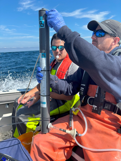 Two men on a boat holding a water filter device.