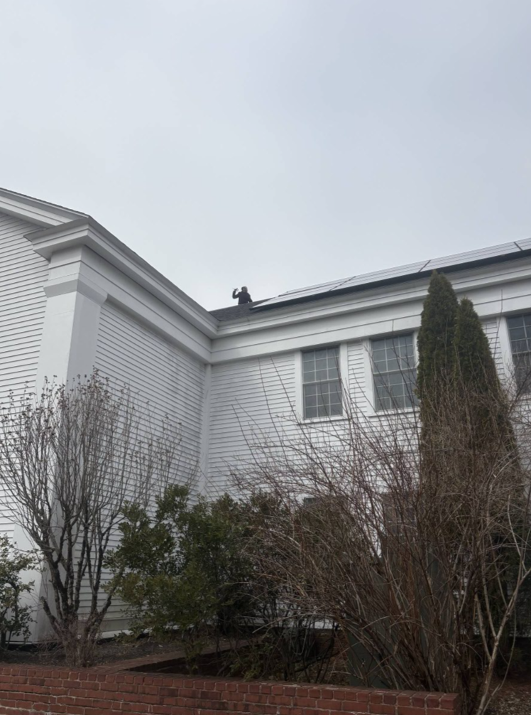 Woman on roof of building with solar panels.
