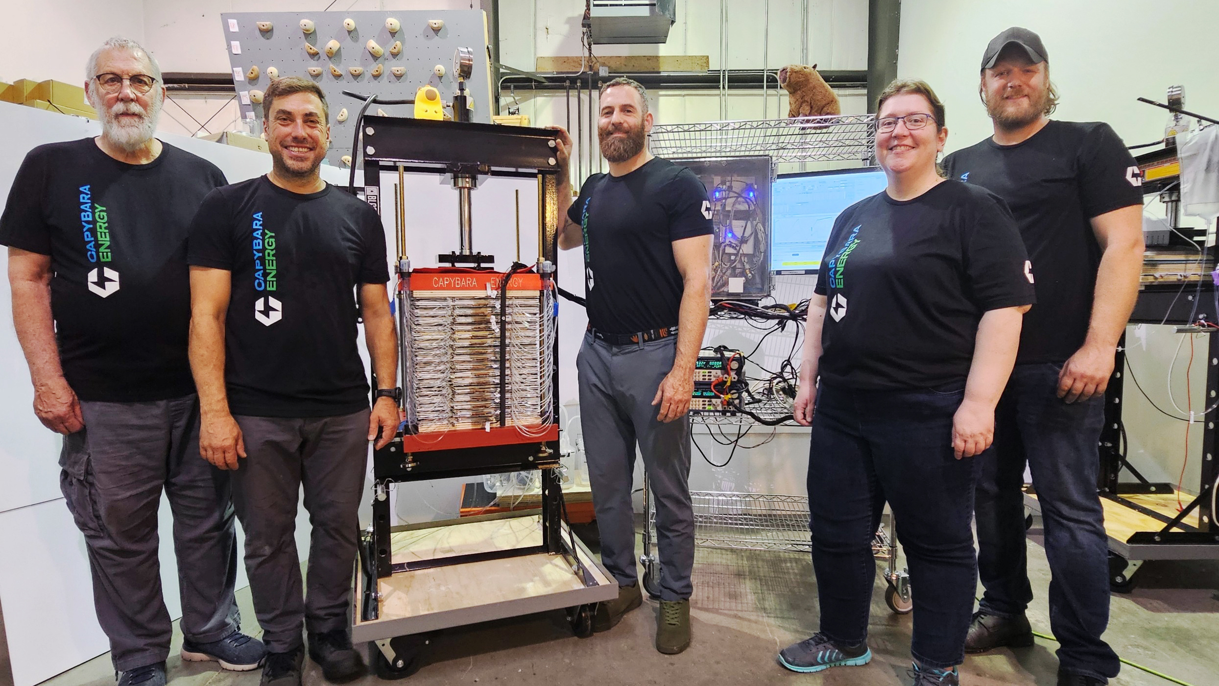 Five members of team Capy stand before one of their storage cells.