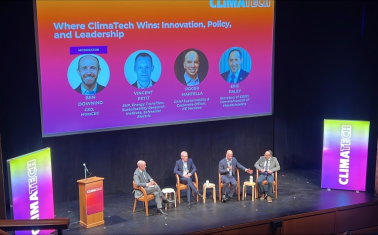 A panel of people speaking on a stage. 
