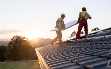 Solar installers work on a roof installing a solar panel array