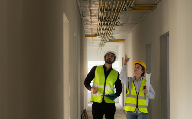 Engineers in hard hats inspecting piping on ceiling