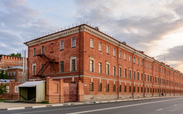 Image of an old brick industrial building on the side of a road in an urban area.