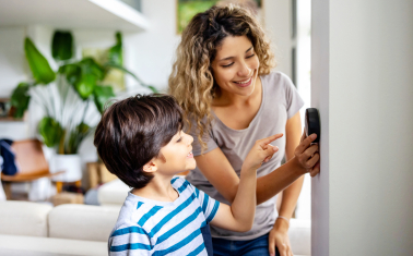 Household adjusting a smart thermostat to manage home energy use.