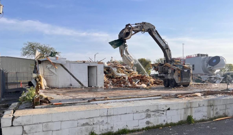 An excavator and wildcat work to demolish a structure