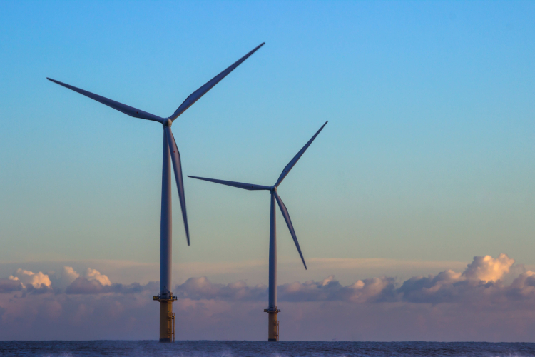 Two offshore wind turbines on an early evening