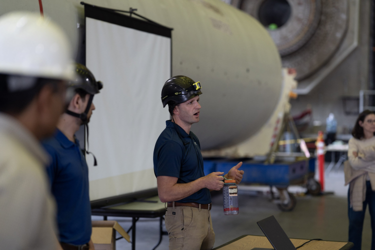A man in a hard hat speaking to a group.