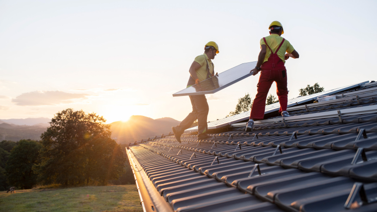 Solar installers work on a roof installing a solar panel array