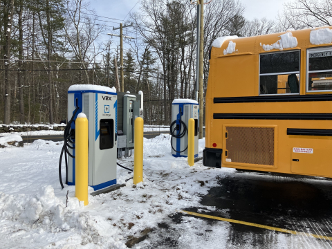 Two bi-directional chargers sit next to electric school buses at Acton-Boxborough Regional School District.