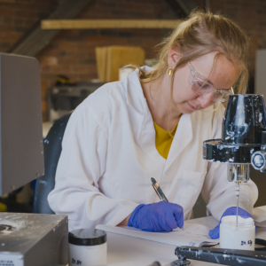 A scientist takes notes while testing paint samples in a lab.