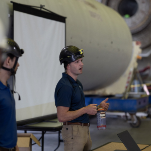 A man in a hard hat speaking to a group.