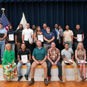 Graduates and instructors smile from a stage