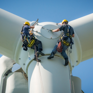 Two men, suspended from top of wind turbine performance maintenance. 