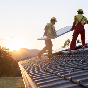 Solar installers work on a roof installing a solar panel array