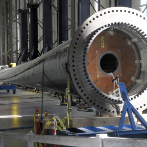 Offshore wind turbine blade lying unattached inside MassCEC’s Wind Technology Testing Center, with the circular blade root in the foreground and the blade extending across the lab floor.