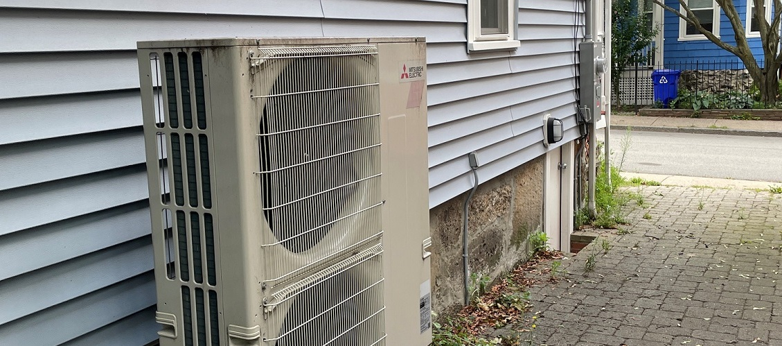 Air-source heat pump outside house on urban street