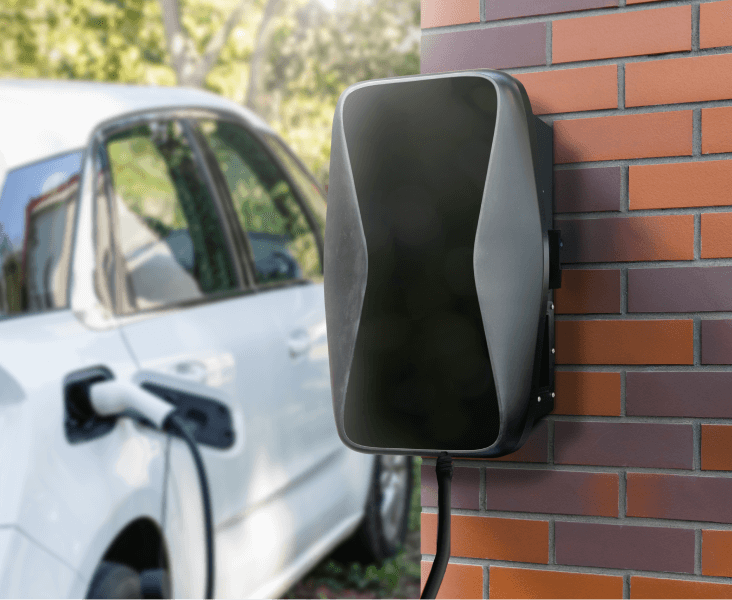 Wall-mounted residential EV charging station installed on a brick wall with electric car plugged in.