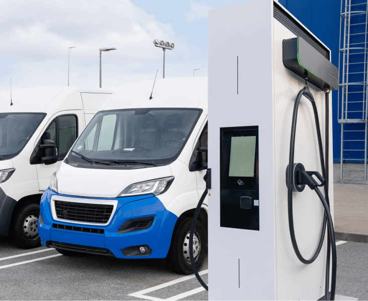 Commercial electric vehicle charging station with electric delivery vans parked and charging.