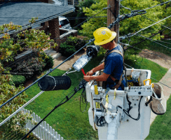 Utility worker in a bucket truck repairing overhead electrical power lines.
