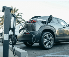 Electric SUV plugged into a public EV charging station in an outdoor parking area.