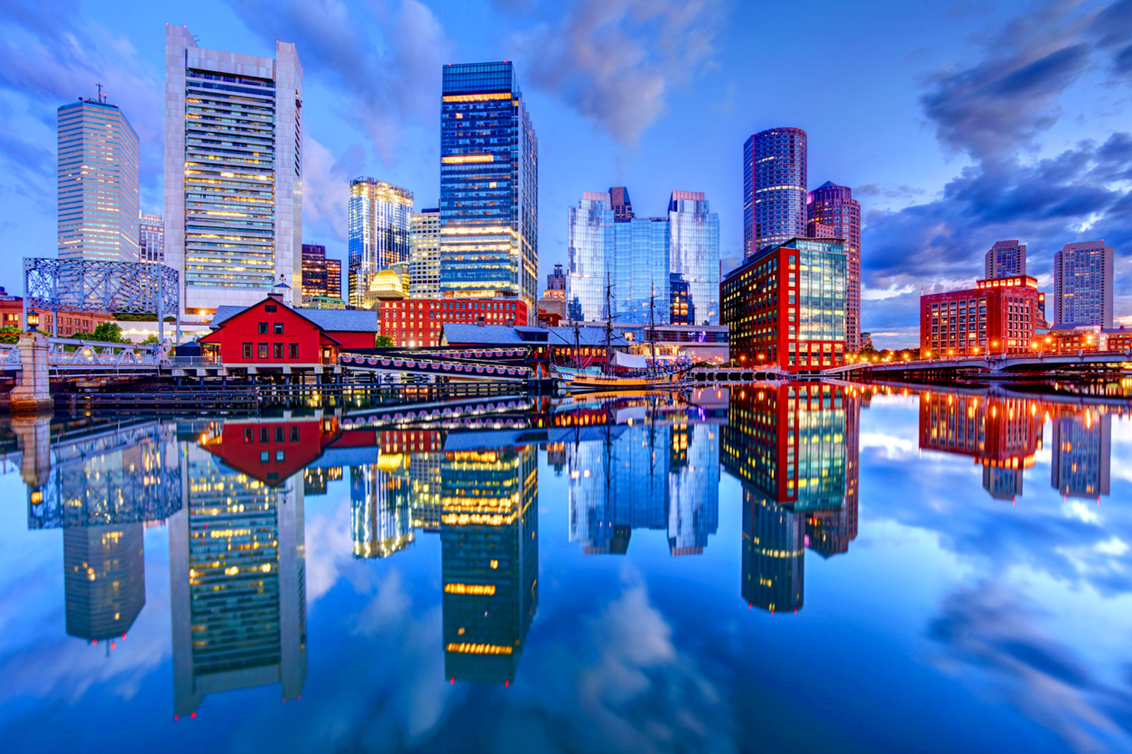 Calm harbor water reflects the Boston skyline at dusk