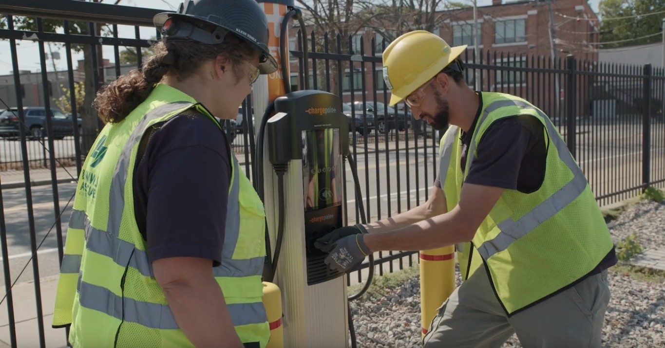 Two maintenance workers repairing a public electric vehicle charger