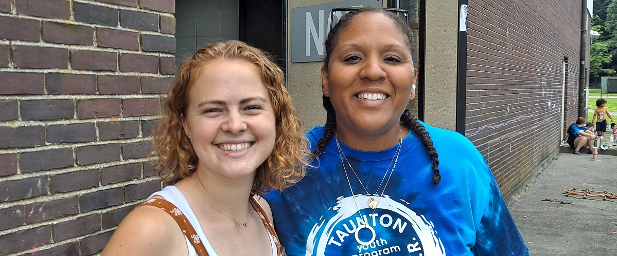 Two smiling young women, one wearing Taunton youth program t-shirt