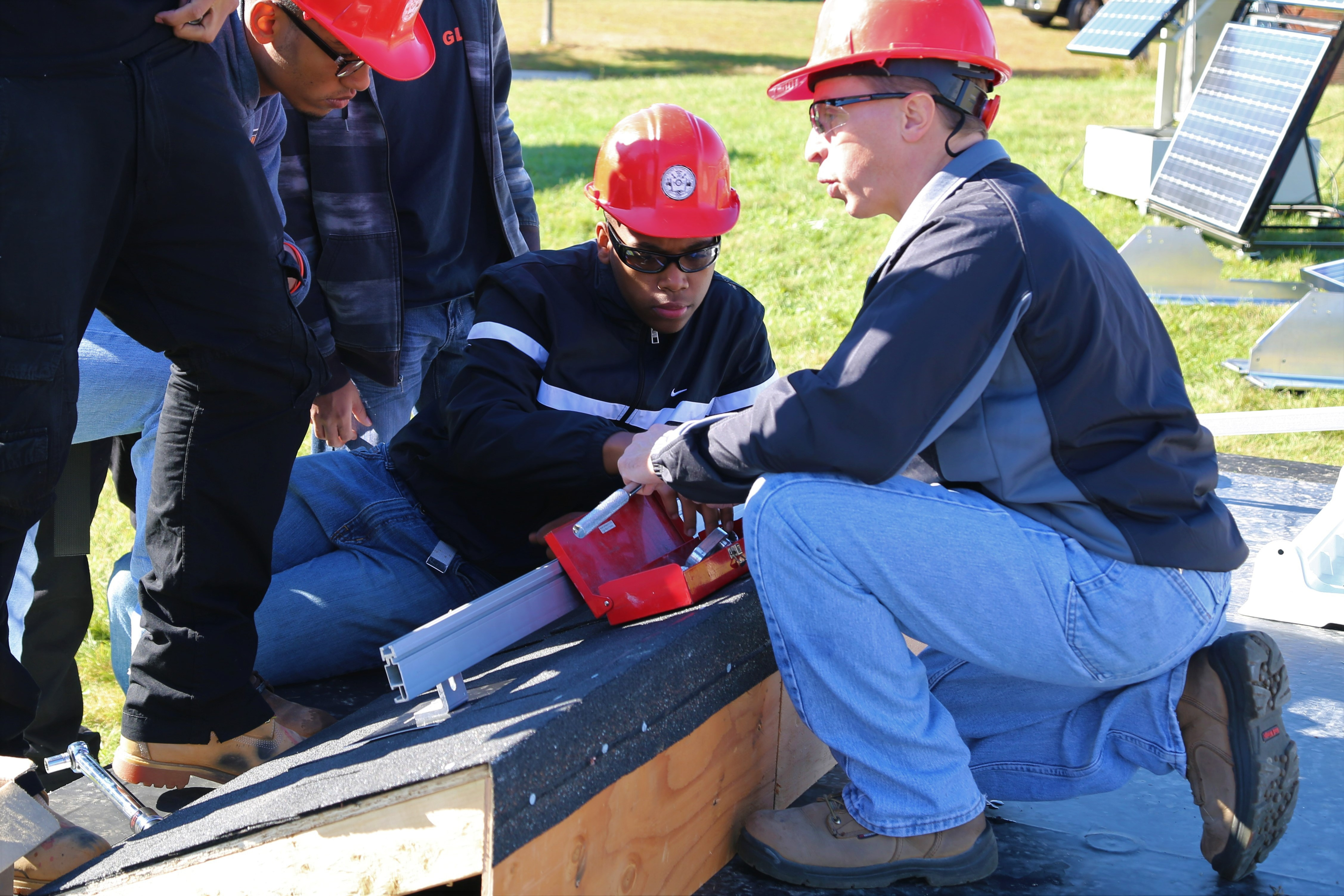 Trainer and trainees examining solar module mounting