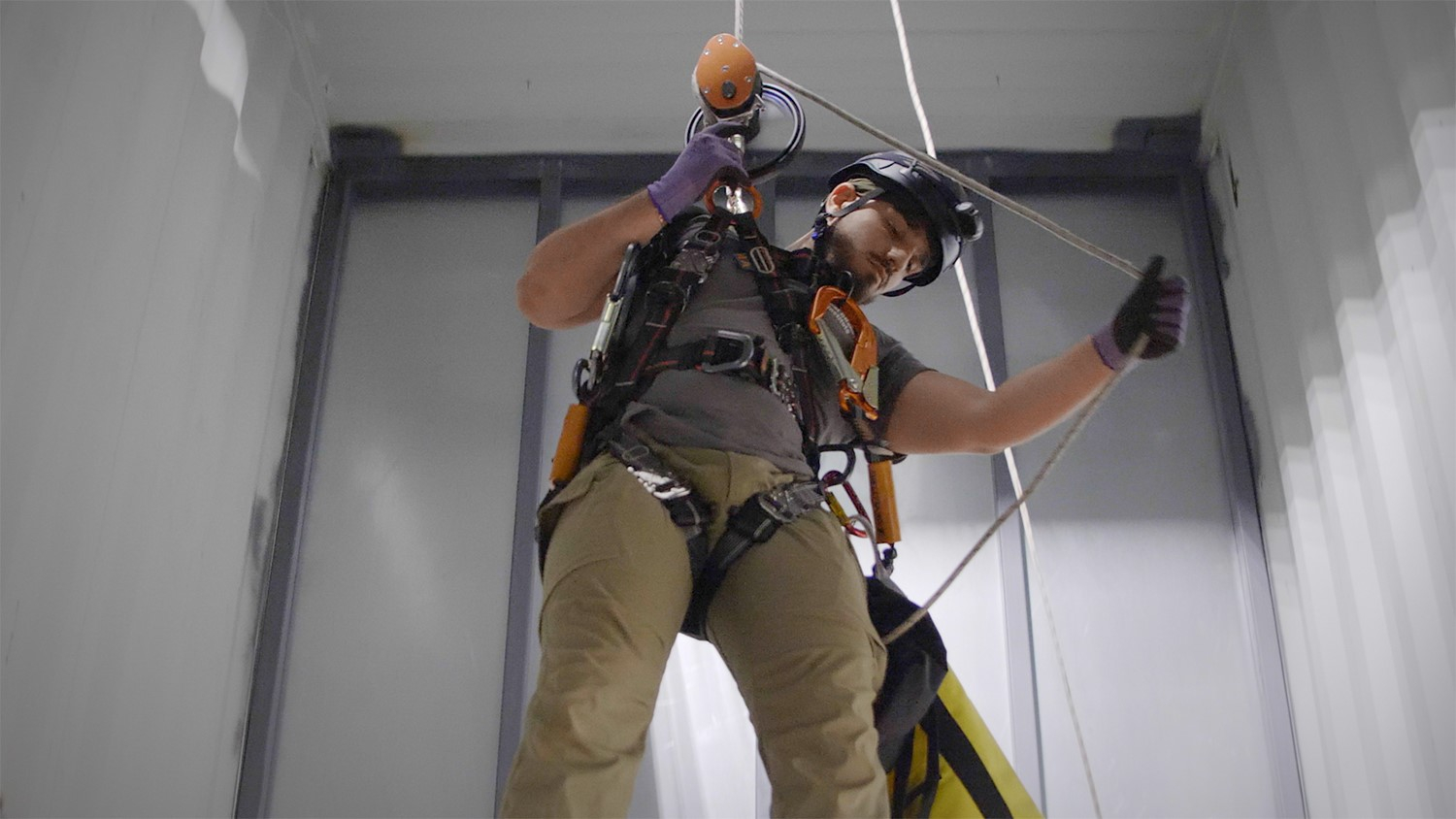 Man hanging in harness in training facility