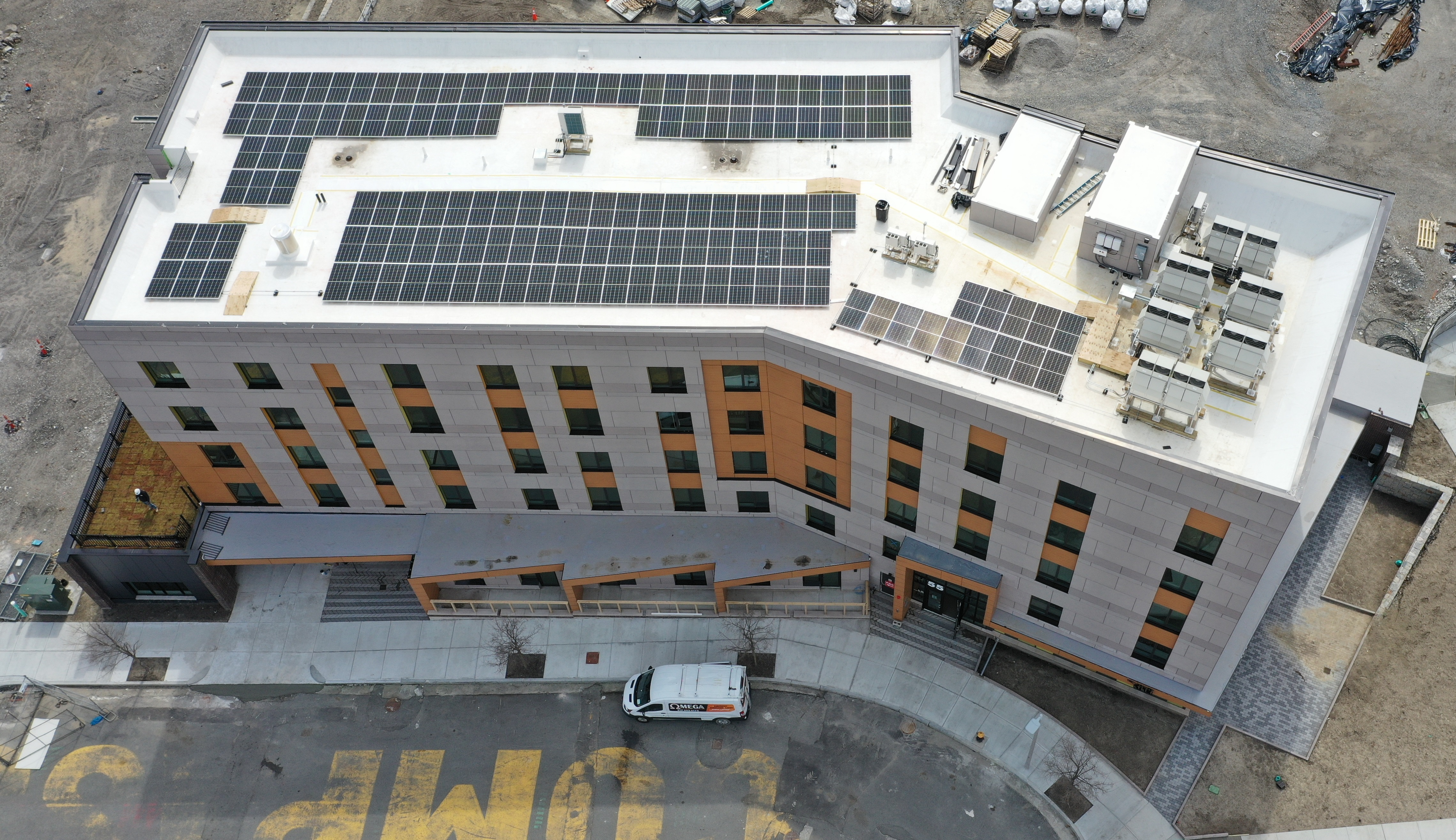 Aerial view of 4-story apartment building with solar panels on roof