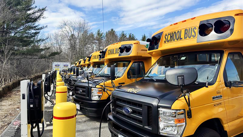 Lawrence Public Schools' Type A schools buses parked and connected to their associated Level 2 (AC) chargers to fuel up before completing routes.