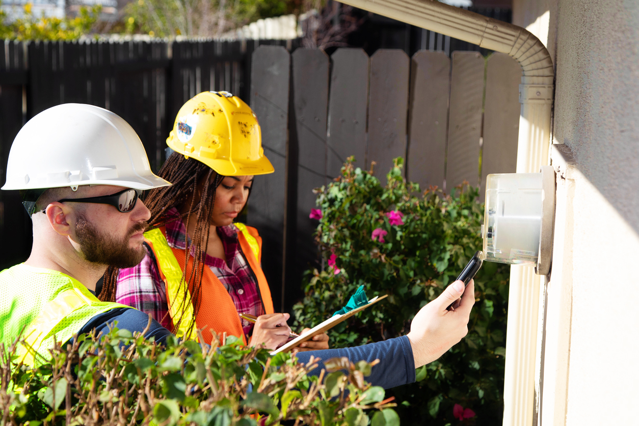 Utility workers inspect an electric meter. 