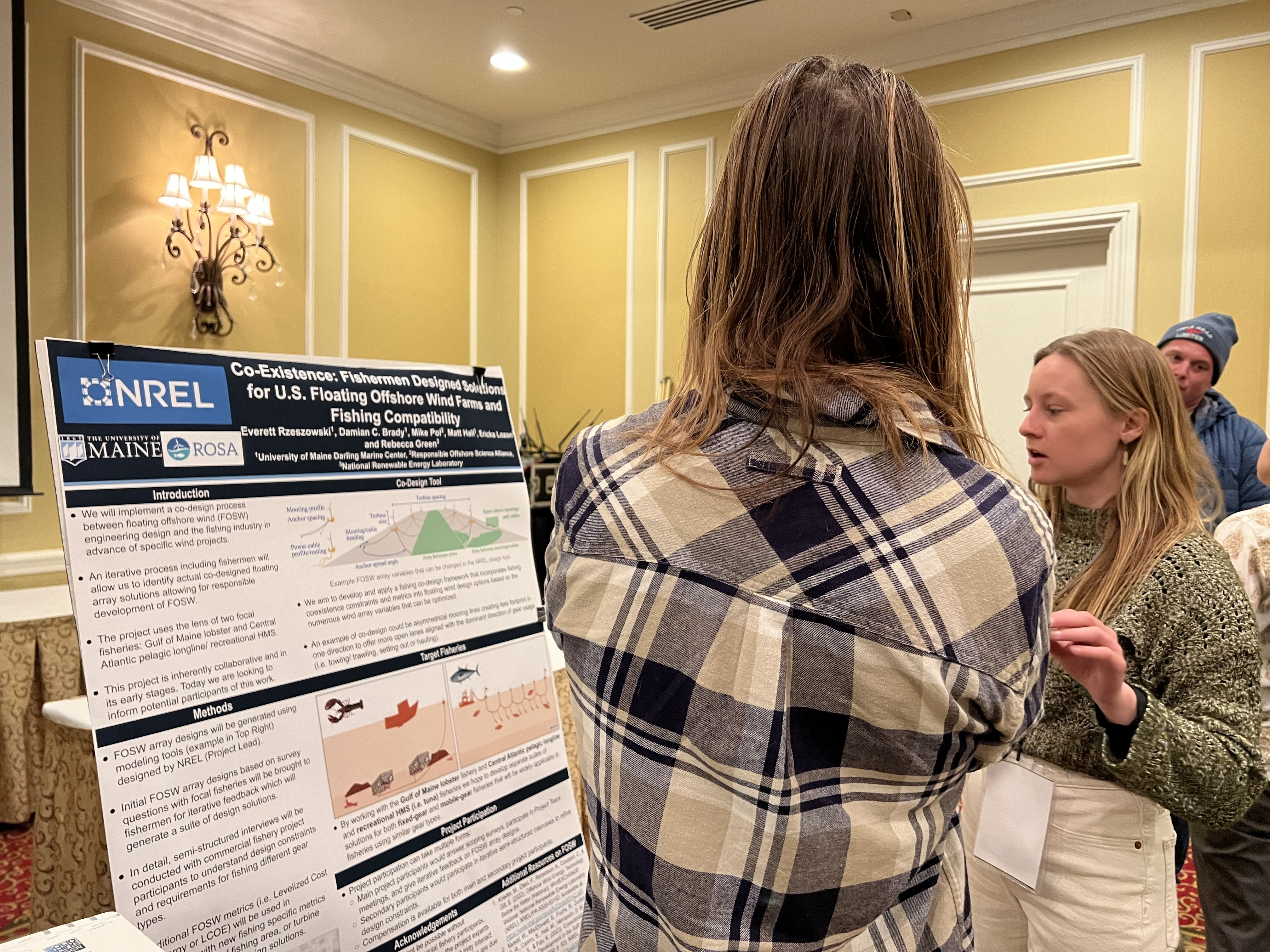 Two people standing in front of a display board with information and data.