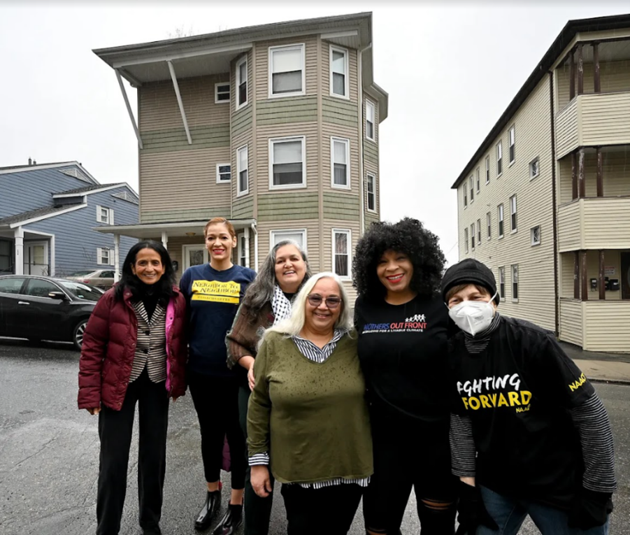 Community organizers working with Worcester HEART stand in front of one of the triple-deckers