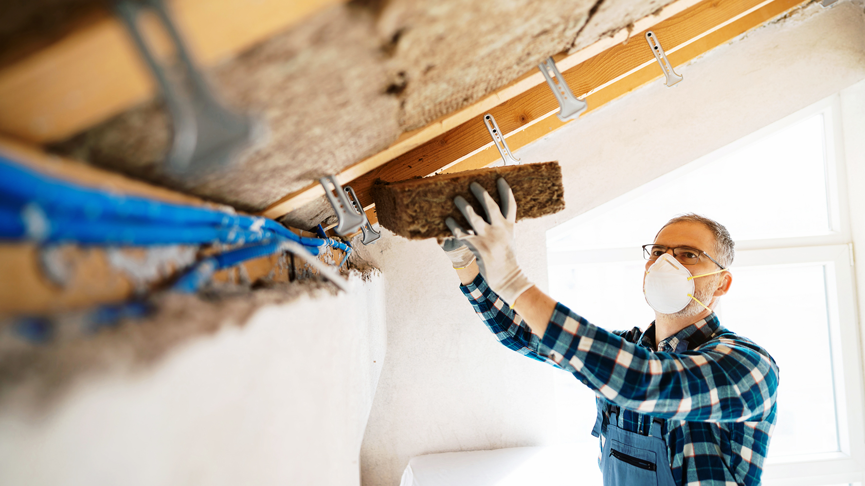 Contractor installing high‑performance insulation in a residential ceiling to improve energy efficiency and building performance, supporting MassCEC High Performance Buildings initiatives.